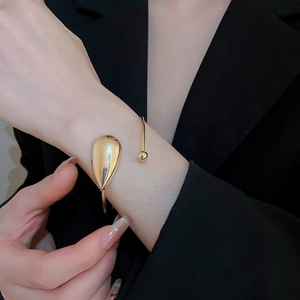 Polished gold drop bangle on model wearing black blazer for a minimalist look