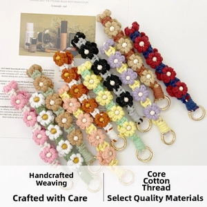 Macro view of handmade woven daisy charms with cotton cords and gold metal clasps