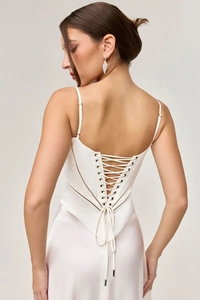 Detail of white satin dress featuring back lace-up closure and elegant lace trim edges