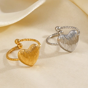 Minimalist gold and silver heart rings with textured finish on silk fabric background