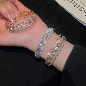 Close-up of sparkling three-layer zircon bangles in rose gold and silver finishes