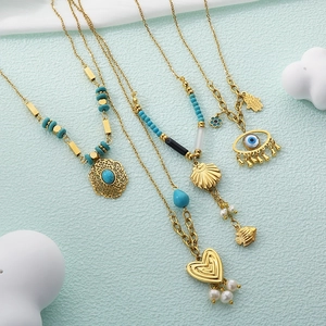 Detail of 18K gold-plated necklaces with turquoise, sea shells, and pearls on soft background