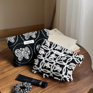 Detail of canvas pouches with butterfly embroidery and lace texture on a wooden table