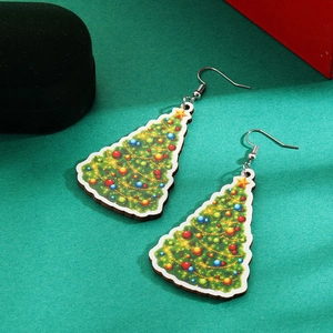 Close-up of green Christmas tree drop earrings on a textured background for gifting