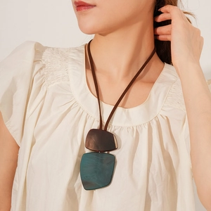 Detailed close-up of irregular wood and teal resin pendants on a brown leather cord