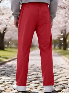 Detail view of red joggers featuring back pocket and white side stripes in park setting