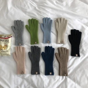 Guantes de punto coloridos en nueve colores como azul y camello sobre tela blanca