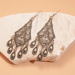 Detailed macro shot of vintage bohemian hollow flower earrings with teardrop fringe