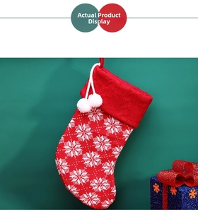 Detail of red knit Christmas stocking with white snowflake patterns and plush pom-poms