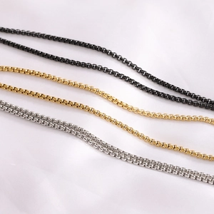 Detailed view of woven metal chains in black, gold, and silver stainless steel finishes