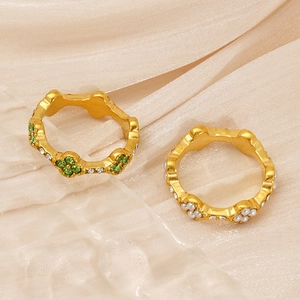 Detailed macro of vintage style gold rings with green clover crystals and white pearls