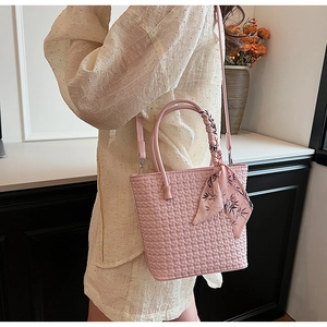 Detail of pink woven bucket bag with elegant bamboo leaf silk scarf on the handle