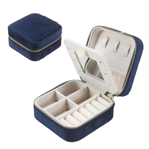 Detail of navy blue velvet jewelry box with gold zipper, interior mirror, and compartments