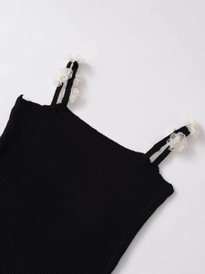 Close-up detail of black knit camisole top with 3D white fabric flower decoration