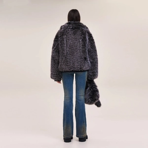 Rear view of a model in distressed flare jeans and a grey faux fur jacket with matching bag