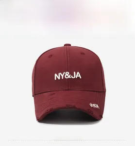 Close-up of distressed brim details and white embroidery on a burgundy baseball cap