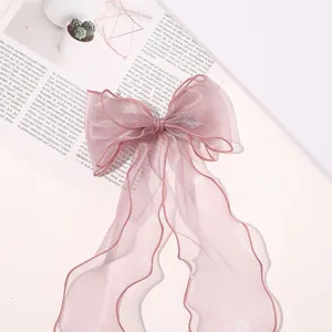 Close-up of pink organza bow hair clip with ribbons on elegant decorative background