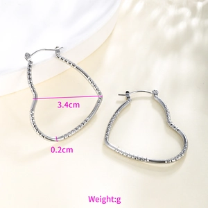 Detail view of silver heart hoop earrings with etched texture and 3.4cm width dimension