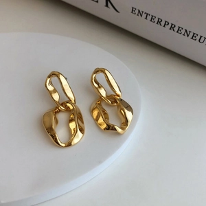 Macro detail of irregular gold double-hoop earrings with textured lava finish