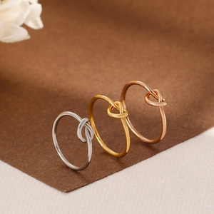 Three minimalist knot-style rings in gold, silver, and rose gold finish stainless steel