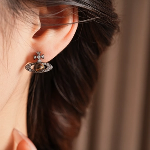 Détail de boucles d'oreilles Saturne en argent avec œil de tigre et zircon sur modèle
