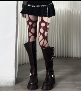 Close-up of distressed dark red distressed fishnet stockings with chunky buckled boots