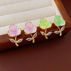 Detailed close-up of crystal flower earrings with gold plating and zircon leaf accents