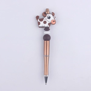 Close-up of cute cow silicone bead pen with brown and white cow charm on a bronze barrel