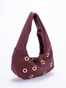Detail view of burgundy suede hobo bag with large gold metal eyelets and soft texture