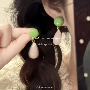Détail de boucles d'oreilles en perles vertes et roses avec design en résine goutte