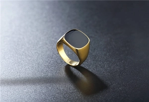 Close-up of polished gold-plated signet ring with square black enamel inlay for men