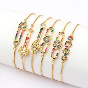 Detail of diverse gold bracelets with vibrant colored zircons on a white display pillar
