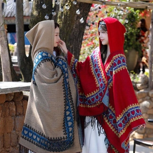 Détail de ponchos ethniques en kaki et rouge avec motifs de cœur et finitions à franges