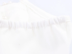 Detail of elegant white fabric with pleated texture and delicate pearl accents on the dress