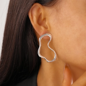 Detailed shot of irregular silver geometric metal earrings on a model's ear