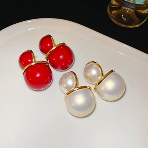 Gros plan de boucles d'oreilles boules rouges et perles sur un plateau en céramique