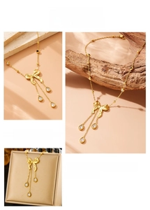 Détails d'un collier nœud doré avec trois pendentifs en cristal et chaîne à billes
