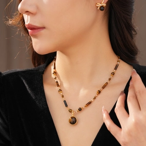 Close-up of model wearing gold tiger eye necklace set with elegant bow earrings