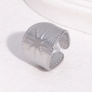 Macro detail of wide silver stainless steel ring with star relief and vertical texture