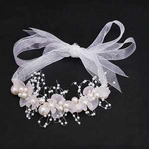 Detail aus weißen Perlen und Blumendraht auf Brautschmuck mit Organza-Schleife