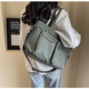Detail of green corduroy tote bag with dual front zippers and removable shoulder strap