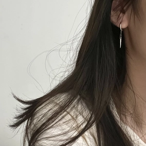 Silver chain earrings with long spike pendant shown on a female model for scale