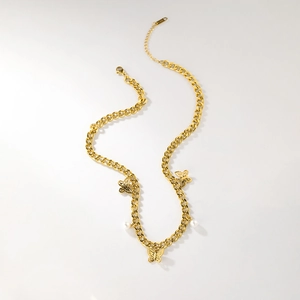 Détail de la chaîne en acier titane doré avec pendentifs papillon évidés et perles