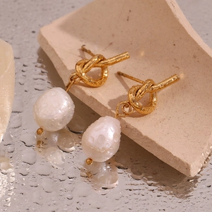 Macro view of knotted 18K gold plated earrings with white teardrop freshwater pearls