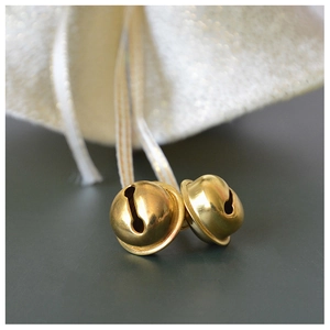 Close-up of golden Christmas bells with pinecone accents and ribbon for holiday decor