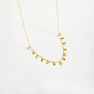 Elegant gold S925 silver necklace featuring pear-shaped zirconia drops and metallic charms