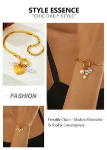 Detail view of gold heart charm and teardrop crystal on mixed snake and link chain bracelet
