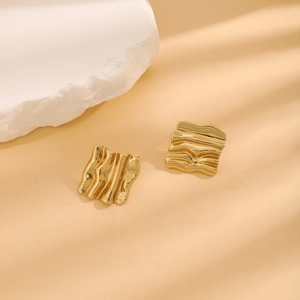 Detailed macro view of gold square earrings with unique lava texture and artistic wavy design