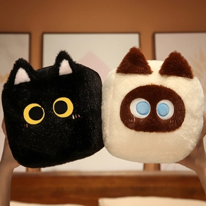 Detail of plush square cat pillow in black and cream faux fur with embroidered face