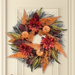 Couronne d'automne de Thanksgiving avec citrouilles et dahlias sur une porte claire